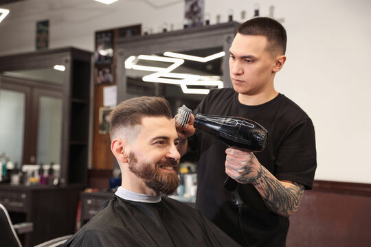 Stylist blow drying man's hair in barbershop