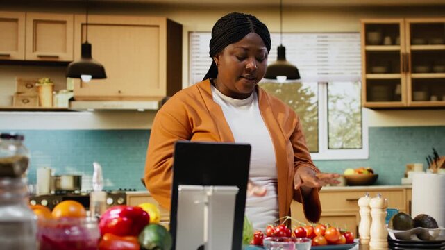 African american influencer answering questions in the comments, engaging with the audience online after livestream. Woman content creator filming homemade food vlog, making a recipe.