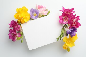 Naklejka premium Beautiful freesia flowers and blank card on white background, top view