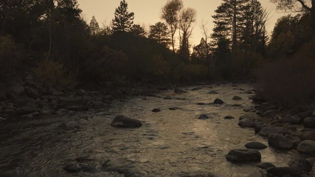 An aerial flyover the Cache La Poudre river with the setting sun near Rustic, CO