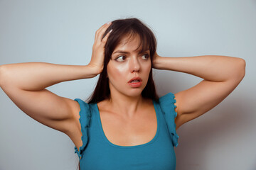 Fototapeta premium Woman shows surprise while touching her hair against a plain background, conveying emotions of shock and curiosity in a beauty-focused lifestyle moment