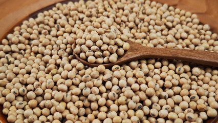 Obraz premium Soybeans in a wooden spoon on plate.