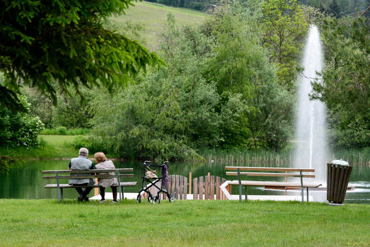 Elderly couple by the side of a lake with fountain