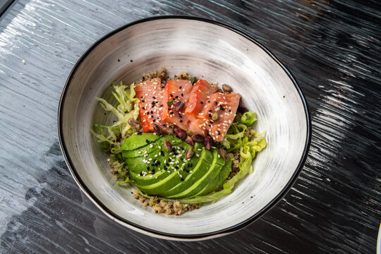 Salmon, avocado and quinoa bowl with lettuce, pistachios, and sesame seeds