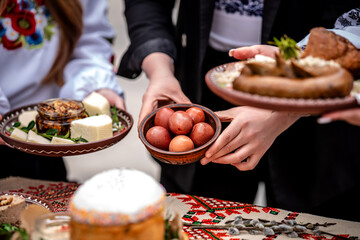 Hands holding traditional Ukrainian Easter food and dyed eggs