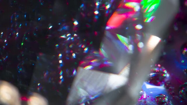 Diamond Facets Sparkle in the Dark. The light passes through the facets of a slowly rotating diamond and creates repetitive sparkling highlights and rainbow colors