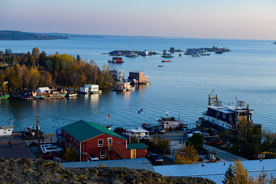 Colorful houseboats and fishing vessels docked along shoreline of Great Slave Lake in Yellowknife at dusk
