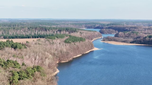 Aerial northern Poland farms forest lake descend. North west Poland. Spring season, Trails, rivers and lakes. Shore grass and forest on the edge of the water. Farm rural nature landscape. Recreation. 