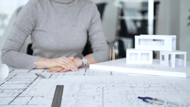 Handshaking between two architects finalizing a construction project deal, business partners agreeing on engineering blueprints and architectural models in an office, close up