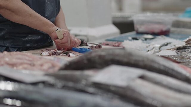 Vendors at busy fish market skillfully prepare a variety of fresh seafood while engaging with customers during peak hours.