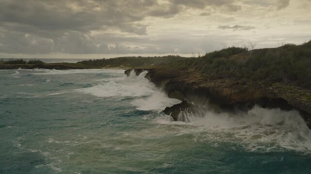 An aerial flyover slow-motion shot of waves crashing on the coast of Kauai in late afternoon, Hawaii
