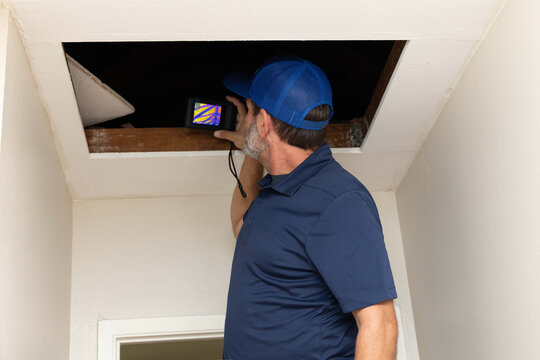 home inspector taking infrared thermography camera pictures of an attic
