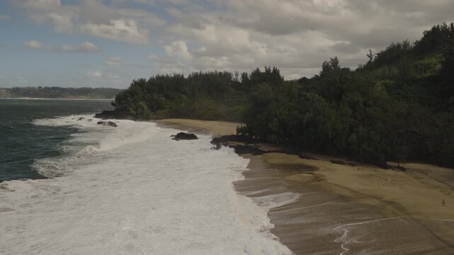 An aerial flyover of Lumaha&Iacute;i beach with crashing waves, Kauai, Hawaii