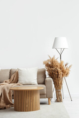Interior of light living room with sofa, table and pampas grass