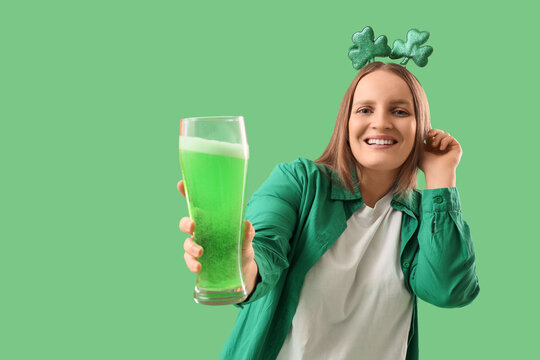 Redhead young woman with beer on green background. St. Patrick's Day celebration