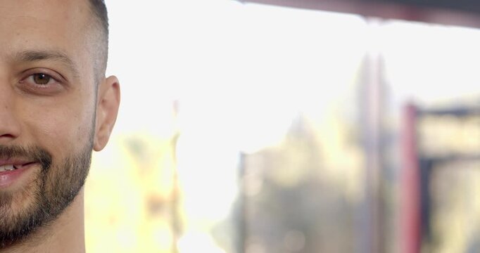 Mid adult indian man smiling after lip corner shift to greet viewer on walkway
