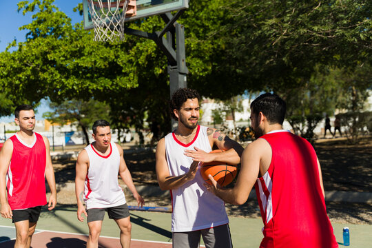 Men playing basketball outdoors, calling for a timeout on a sunny day during a friendly pickup game