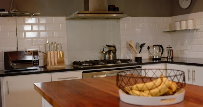 Camera dollying forward and focusing on wire fruit basket on kitchen island, bananas filling frame