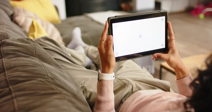 Non-binary person lifting tablet to calibrate screen and adjusting angle on living room couch