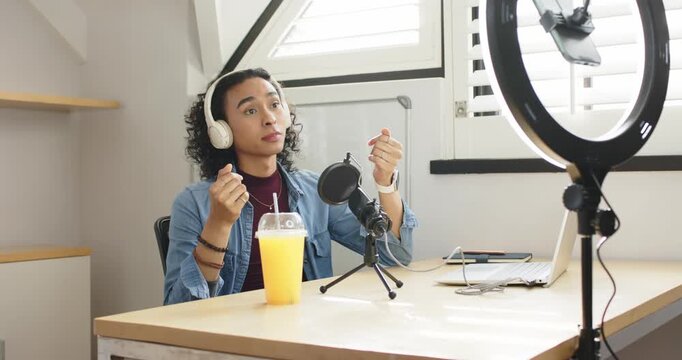 Nonbinary host donning headset talking into mic raising finger at list item summarizing at desk
