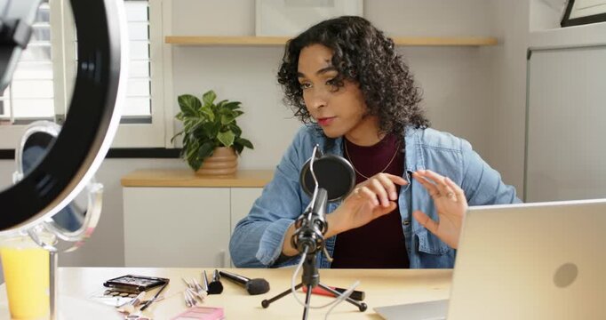 Non-binary creator prepping laptop, ring light and mic, showcasing brushes palette lipstick at desk