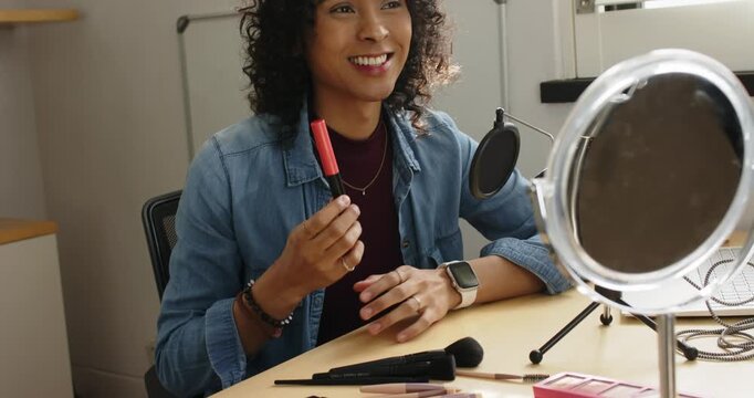 Non-binary creator showing red lip gloss shade before demoing powder brush usage tip at home studio