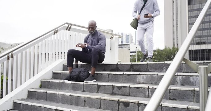Diverse male strangers exchanging smartwatch tips on urban stairs after shoulder tapping