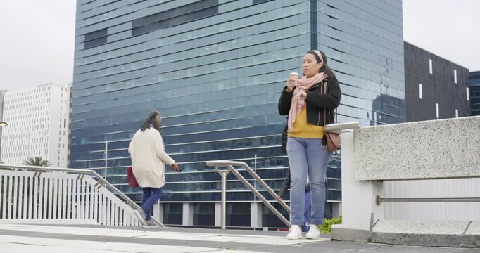 Senior African American woman arriving plaza sipping coffee checking wristwatch waiting on ledge