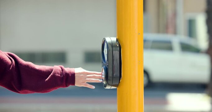 Person's left arm in maroon sleeve pressing walk button on bright yellow pole, needing to cross
