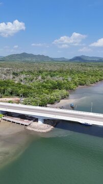 Vertical aerial drone orbit along bridge connecting islands in Koh Lanta Thailand with moving cars tropical landscape 4K