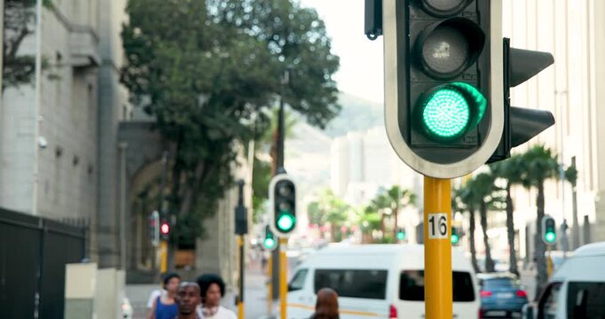 Diverse commuters crossing crosswalk as foreground signal changing green to red, halting traffic