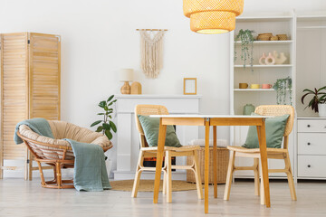 Fototapeta premium Interior of stylish dining room with table, armchair, fireplace and glowing lamp
