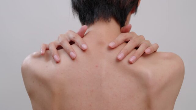 Close-up of asian female touching their shoulder, showing back acne, blemishes, and uneven skin tone. Ideal for dermatology, body skincare, and health concepts.