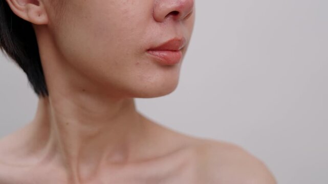Close-up of asian female face showing natural skin texture, enlarged pores, and blemishes on a white background. Ideal for skincare and real beauty concepts.