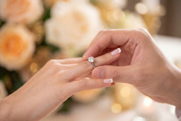 Fototapeta premium Man placing diamond engagement ring on woman finger