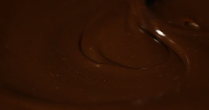 Stirring sweet melted chocolate with spoon, closeup