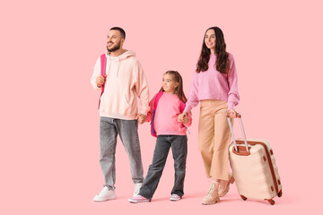 Family of travelers with bags walking on pink background