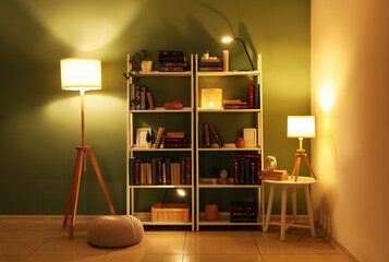 Interior of home library with bookshelves, stool, glowing lamps and ottoman near turquoise wall © Pixel-Shot
