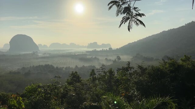 Golden sunrise over mist covered valley and limestone formations at Din Daeng Doi in Krabi Thailand with layered forest, soft haze, and peaceful tropical landscape