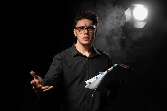 Male screenwriter with scenario on dark background