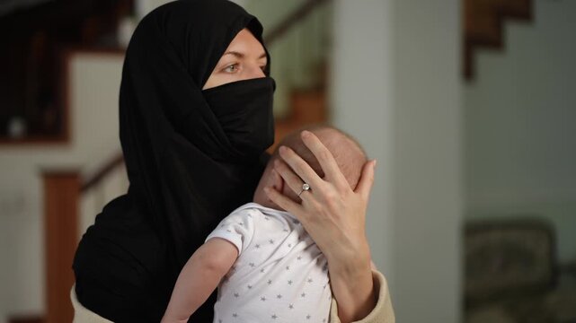 Loving muslima gently caressing and holding her newborn son. The mother is showing affection and bonding with her beautiful new baby