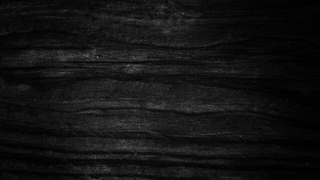 Dramatic black charred wood texture background. Dark burnt timber surface with detailed natural grain, cracks, and rustic charcoal finish for moody aesthetic design.