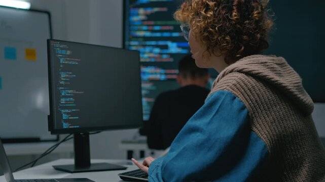 Asian female software engineer and diverse developers working on programming code on computer screens in a modern office. Concept of AI development, coding, and future technology.