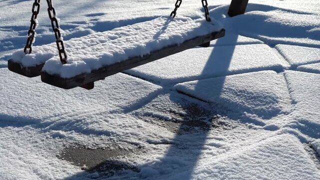 Snowy playground with empty swing set.
