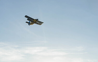 Fototapeta premium Vintage biplane flying gracefully across blue sky