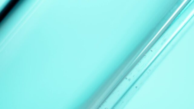 Light blue liquid contained within a diagonal glass tube for chemical analysis. Detailed view of the substance for cosmetic formulation research.