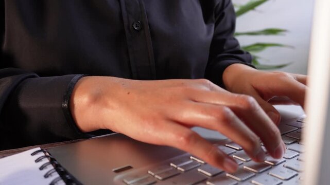 A woman's hands, focused as she works on her laptop, with an animation of various document icons.