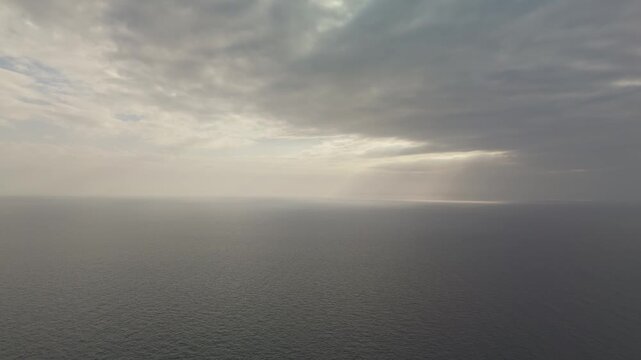 A panoramic aerial view of the Mediterranean Sea featuring calm blue waters, a dramatic cloudy sky, and an expansive horizon in natural daylight.