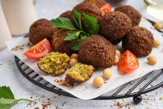 Stand with delicious falafel balls, chickpea and tomato on light background, closeup