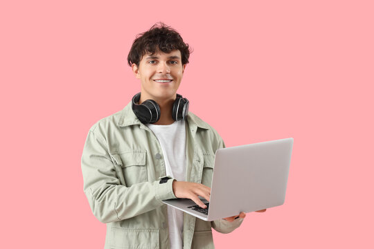Male programmer working with laptop on pink background